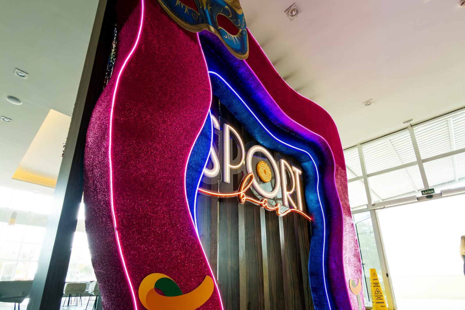 Portal cenográfico do Sport Bar — cortinas glitter, neon e máscara gigante